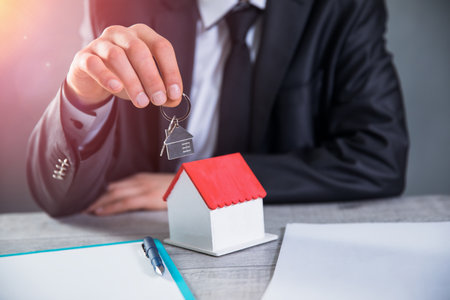 man hand key with house model on deskの写真素材