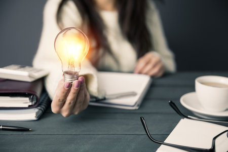 woman hand bulb on office desk backgroundの写真素材