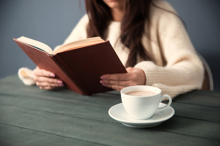 woman reading book with coffee on deskの写真素材