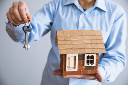 man hand holding house model with keyの写真素材