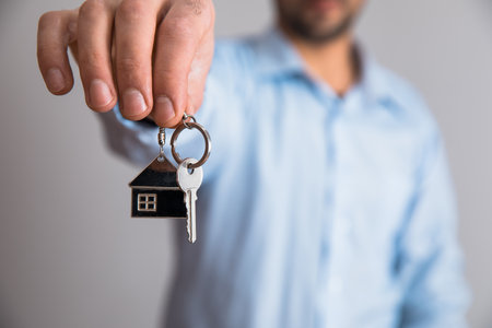 man hand holding house key on gray backgroundの写真素材