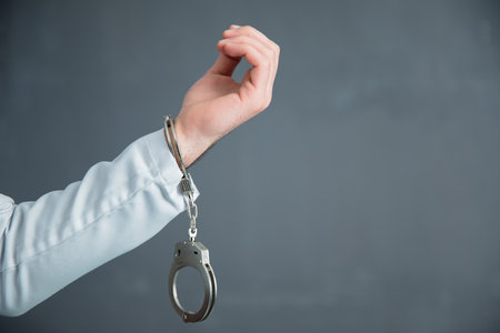 man hand opening handcuffs on dark background