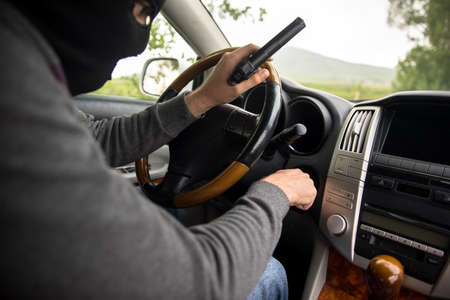 man face mask with hand gun in carの写真素材
