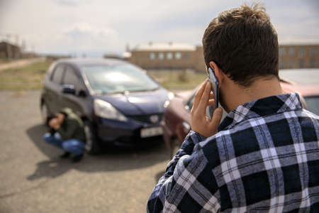 Sad man calling roadside service after car crashの写真素材