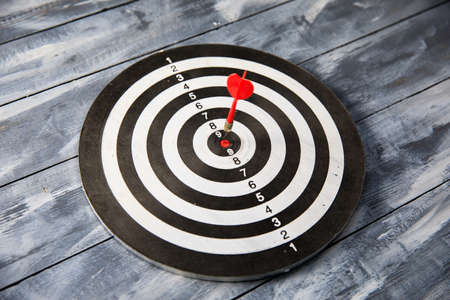 Red dart arrow hitting in the target center of dartboardの写真素材