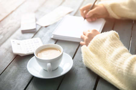 woman hand notepad with cup of coffee on the tableの写真素材