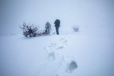 two photographers in snowy mountainの写真素材