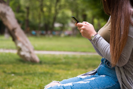 young woman hand smart phone sitting in gardenの写真素材