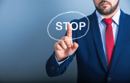 businessman touching stop in screen on blue backgroundの写真素材
