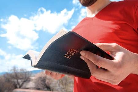 man hand Holy Bible in nature background