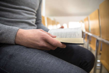man hand Holy Bible sitting on a chair