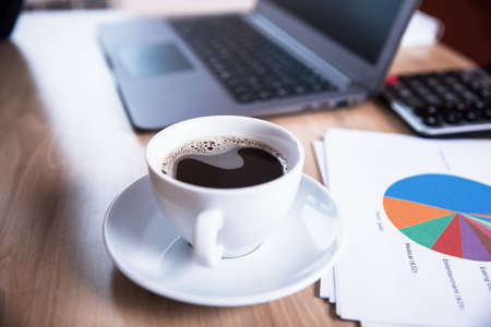 coffee and paper of graph with computer on tableの写真素材