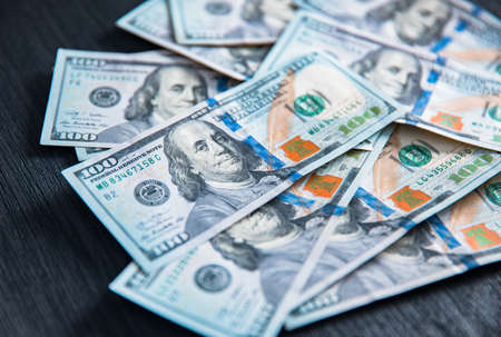 Stack of hundred dollars on black wooden tableの写真素材