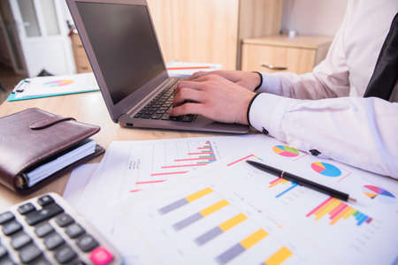 man working in computer and graph paper on desk