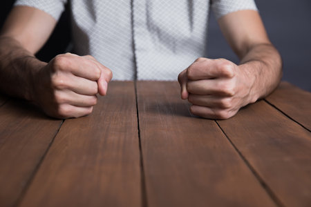 angry man fists on the wooden tableの写真素材
