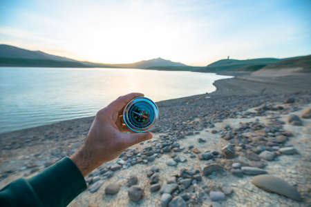 man hand compass in the lake background