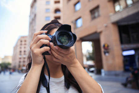 Woman photographer with a professional camera taking a photoの写真素材