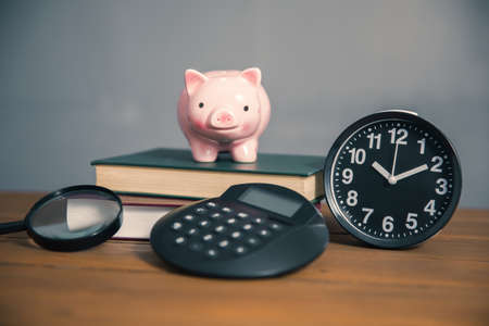 piggy bank on the book and calculator on tableの写真素材
