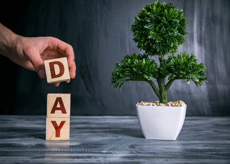 man holding day world in wooden cubesの写真素材