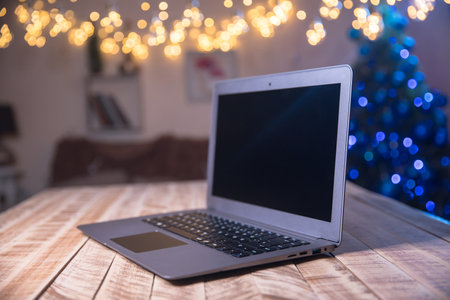 laptop computer on wooden table over christmas lights backgroundの写真素材