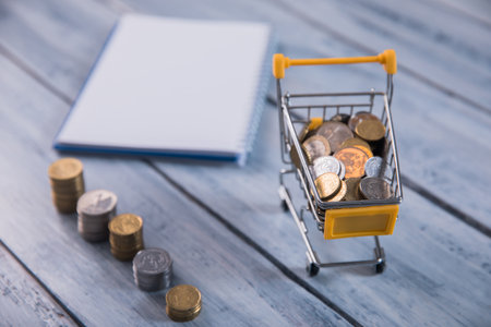 coins with basket and notebook on tableの写真素材