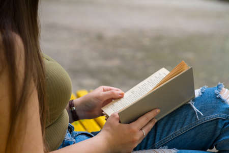woman reading book sitting in streetの写真素材