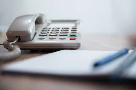 telephone with notebook and pen on tableの写真素材