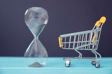hourglass and shopping cart on the tableの写真素材