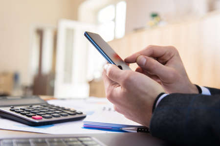 man holding phone in working tableの写真素材