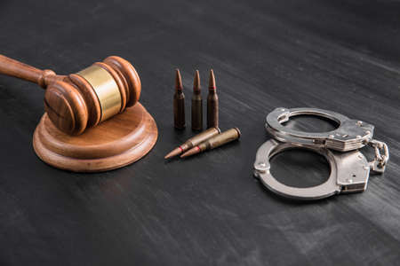judge gavel with bullets and handcuffs on tableの写真素材