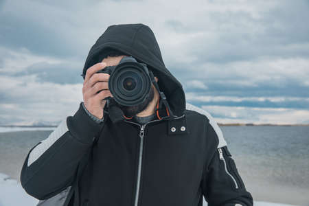 man holding camera on lake backgroundの写真素材