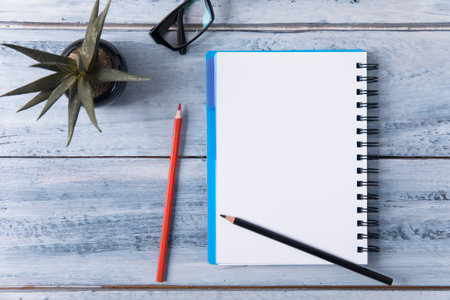notebook with pencils and glasses with cactus on tableの写真素材