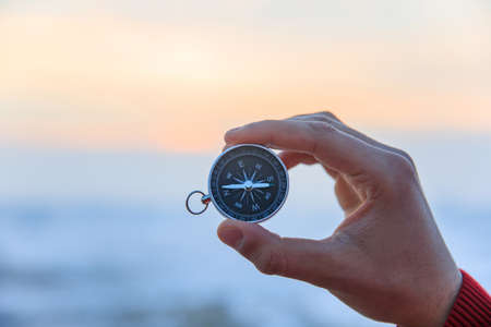 man holding compass in snow roadの写真素材