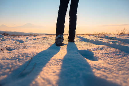 man walking in the snow at the sunsetの写真素材