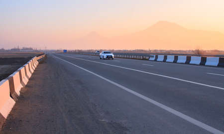 car in asphalt road in Ararat background at the sunset