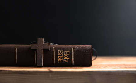 wooden cross with Holy Bible on dark backgroundの写真素材