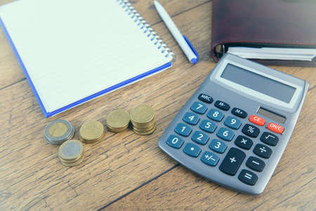 notepad with coins and calculator on table