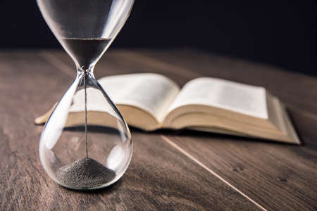 hourgass with book on the wooden background