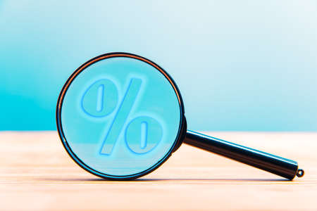 Magnifying glass with a percent sign on tableの写真素材
