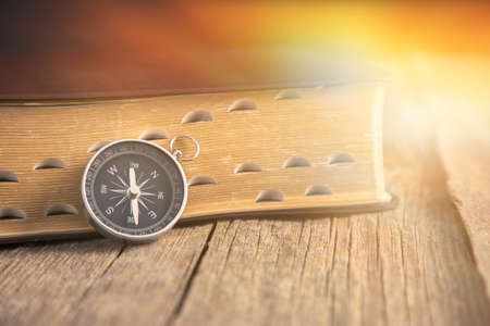 Holy Bible with compass on the wooden background