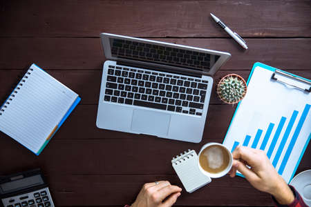 businessman working laptop and hand holding cup of coffee on working table