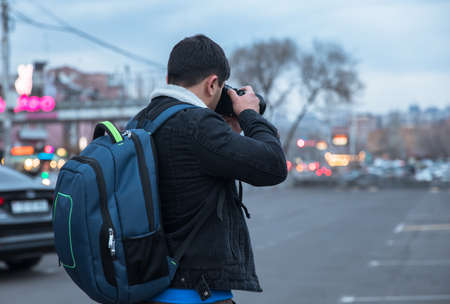 young traveler man holding camera in street