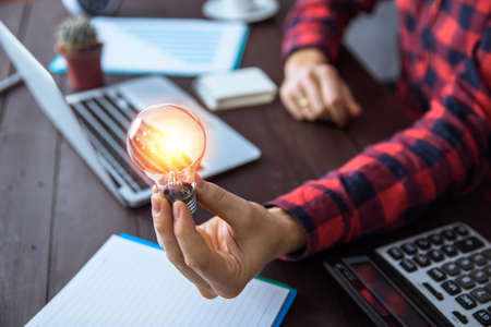 idea concept, man holding light bulb in working tableの写真素材