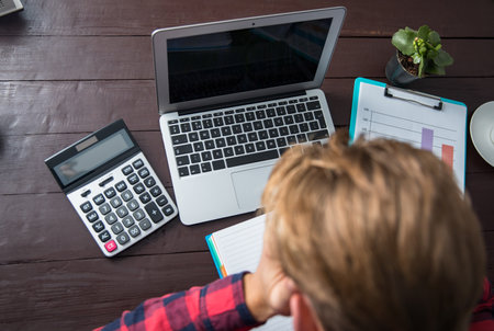 man working computer with graph and calculator on tableの写真素材