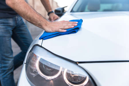 a man cleaning car with cloth in street