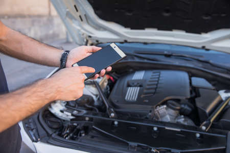 closeup of man with broken car and smart phoneの写真素材