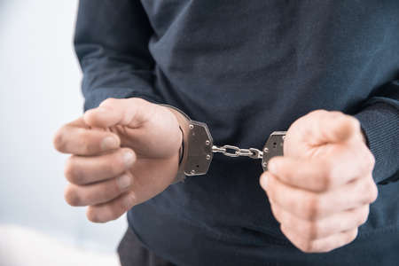 sad man hand handcuffs on gray backgroundの写真素材