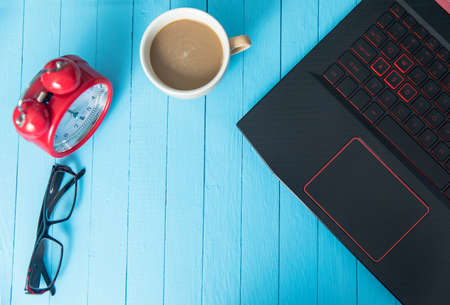clock with glasses and notebook and coffee on blue background