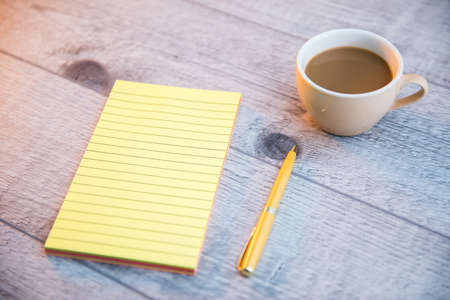 notepad with cup of coffee and pen on tabe