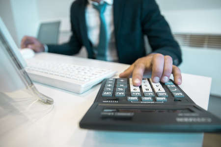 business man working in computer with calculatorの写真素材